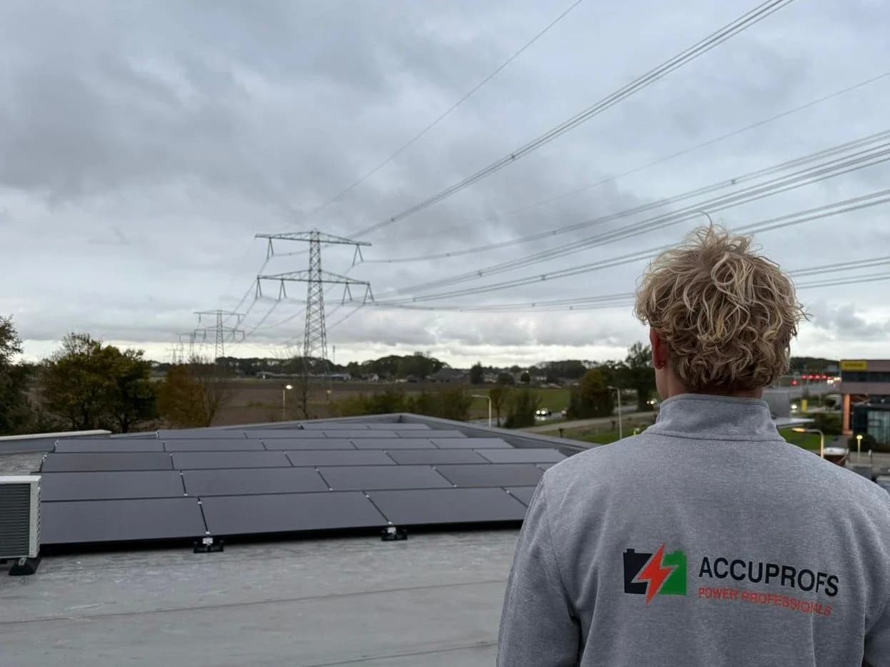 AircoProfs medewerker bij zonnepanelen met hoogspanningsmasten op de achtergrond