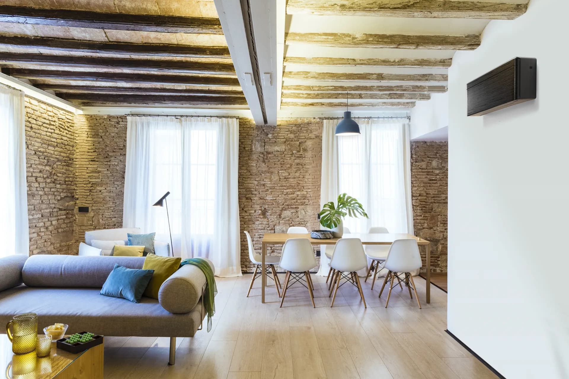 Woonkamer met houten balken en een zwarte airco aan de wand