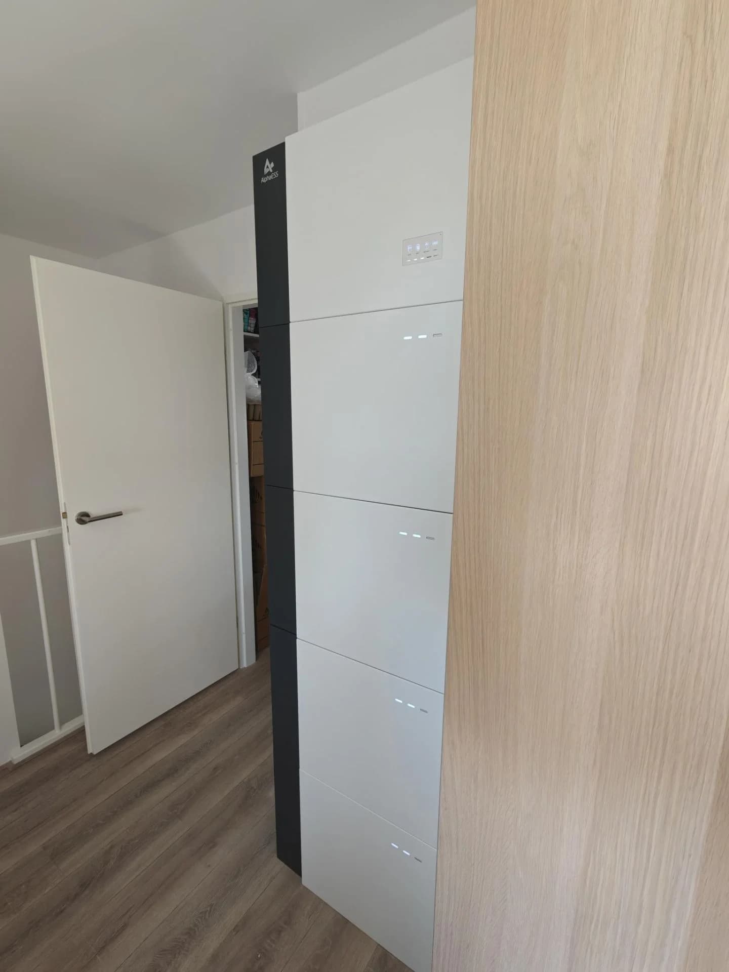 Hoge grijze installatiekast naast een houten wand