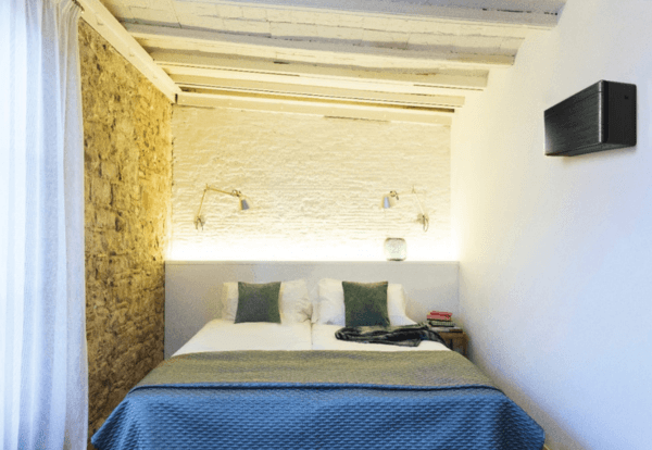 Slaapkamer met houten balken en een zwarte airco aan de wand
