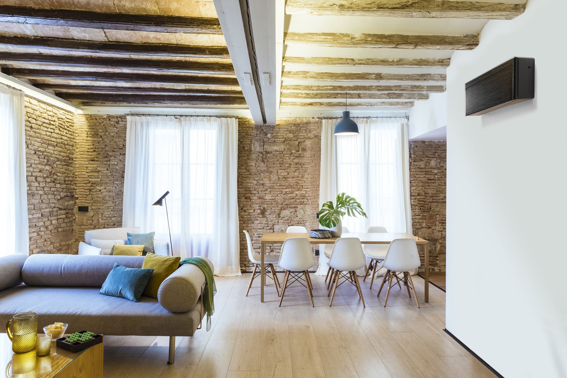 Woonkamer met houten balken en een zwarte airco aan de wand