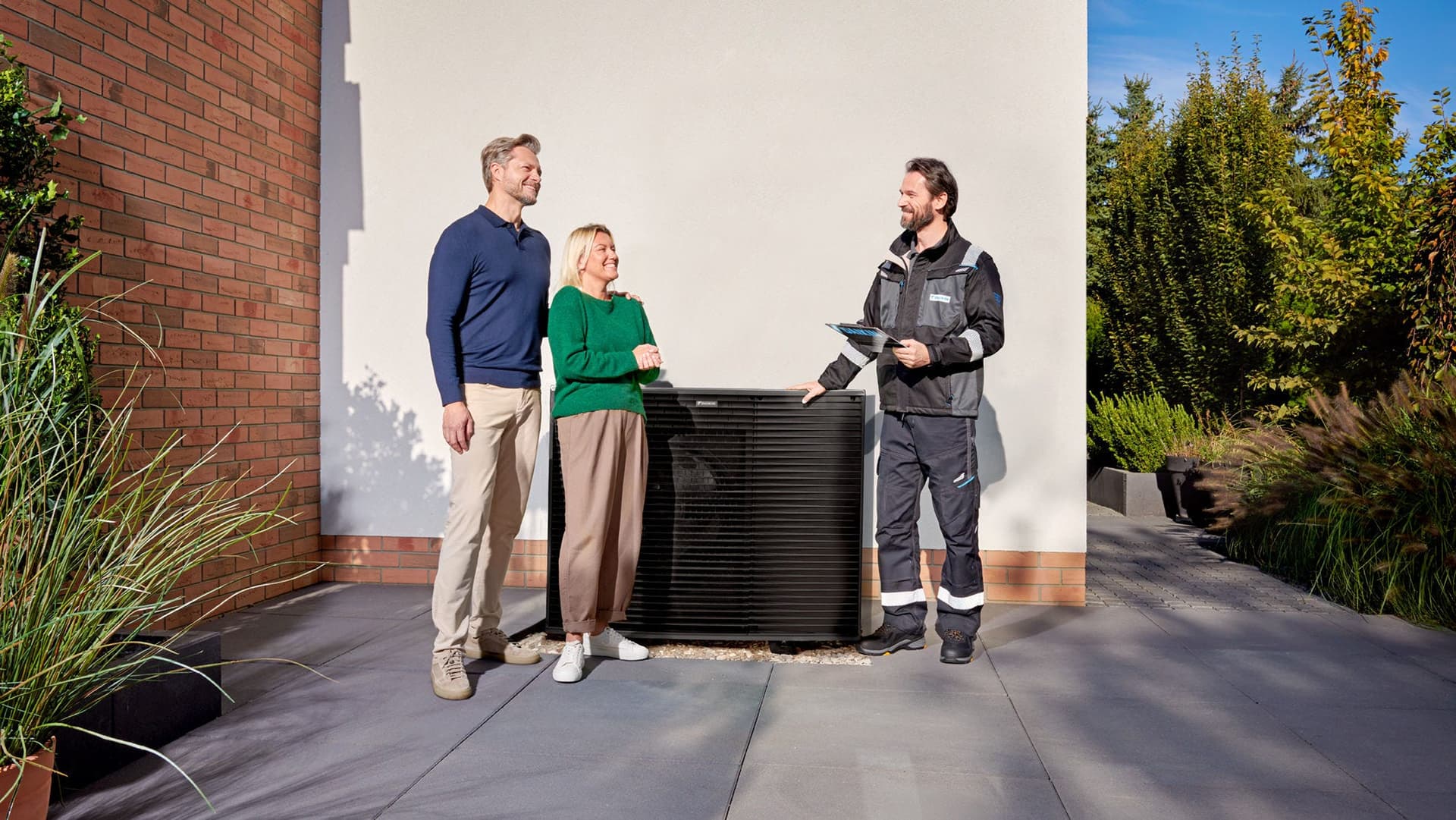 Adviseur en bewoners naast een Daikin warmtepomp bij een woning